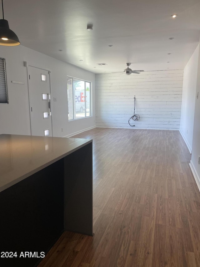 interior space featuring wood walls, ceiling fan, and wood-type flooring