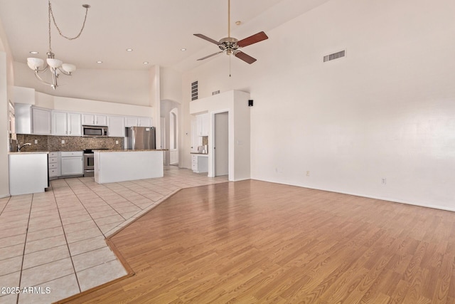 871 W Mesquite St, Gilbert, AZ 85233 - unfurnished living room with a chandelier, light wood-type flooring, a high ceiling, a ceiling fan, and arched walkways