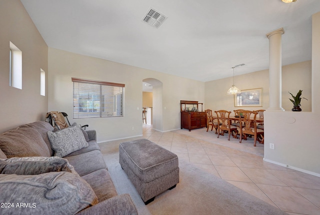 living room with an inviting chandelier, light tile patterned flooring, and decorative columns