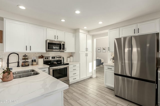 kitchen featuring backsplash, appliances with stainless steel finishes, light stone counters, and a sink