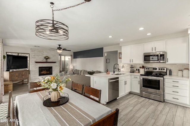 kitchen with stainless steel appliances, a sink, white cabinetry, light wood-type flooring, and backsplash