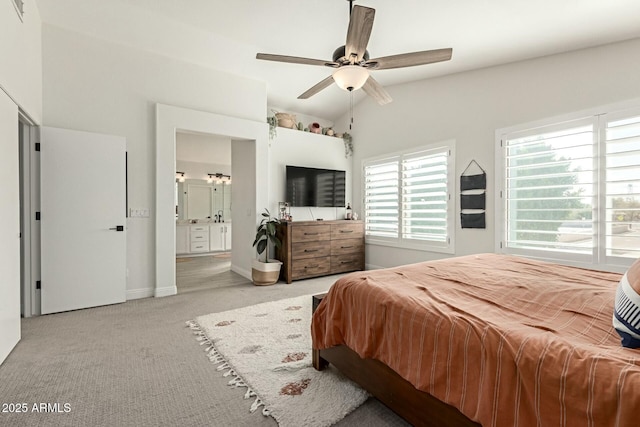 carpeted bedroom with lofted ceiling, baseboards, ceiling fan, and ensuite bath