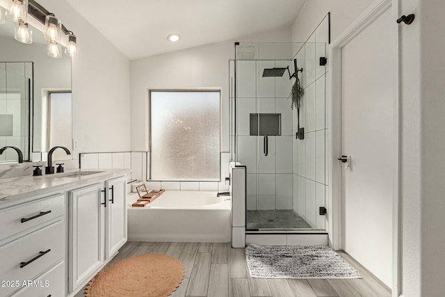 bathroom featuring a garden tub, wood tiled floor, vaulted ceiling, vanity, and a shower stall