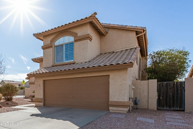 mediterranean / spanish-style home with a garage, driveway, fence, and stucco siding