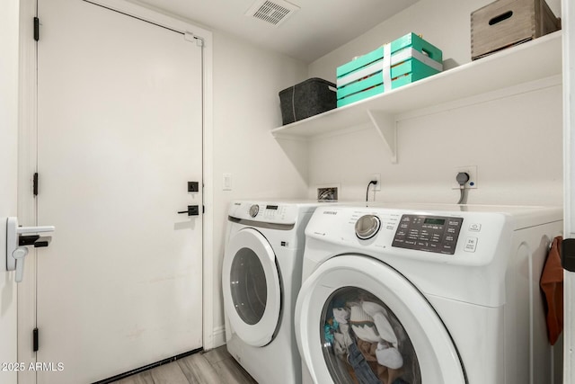 laundry area with light wood-style floors, laundry area, visible vents, and washing machine and clothes dryer