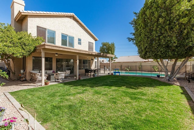 rear view of house featuring a fenced backyard, a chimney, a yard, a patio area, and stucco siding