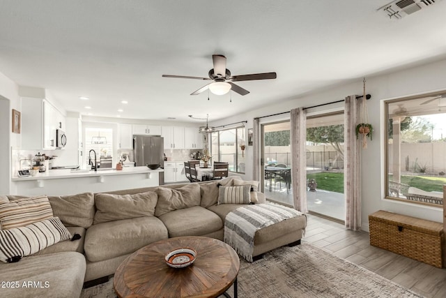 living area featuring a ceiling fan, recessed lighting, visible vents, and light wood finished floors