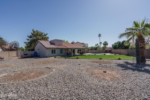 rear view of property featuring a fenced in pool, a patio, a lawn, and a fenced backyard