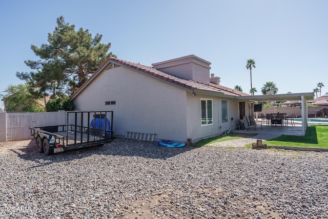 view of property exterior with a tile roof, a patio area, fence, and stucco siding