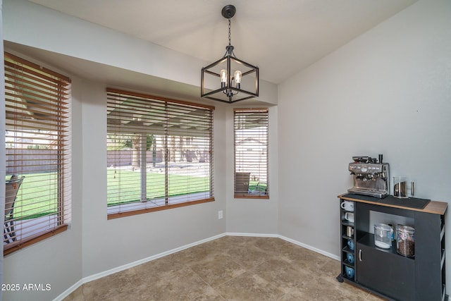 dining room featuring an inviting chandelier, baseboards, and lofted ceiling