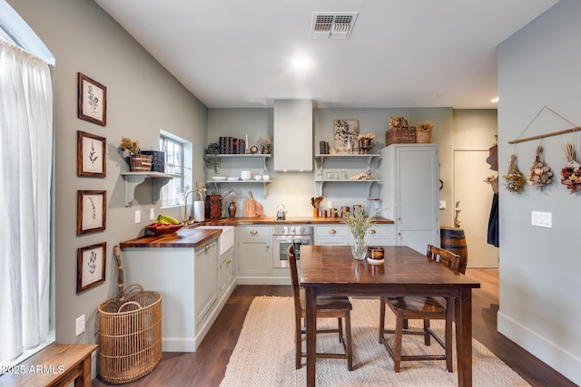 kitchen with wood counters, sink, white cabinets, hardwood / wood-style flooring, and stainless steel oven