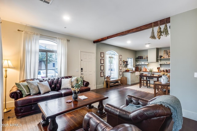 living room featuring beamed ceiling, a healthy amount of sunlight, and dark hardwood / wood-style flooring