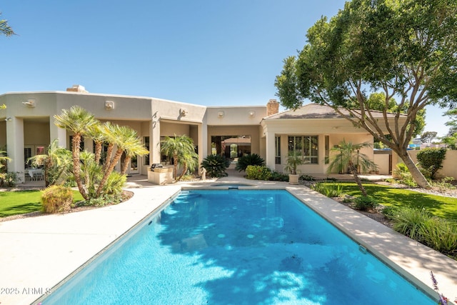 back of house featuring stucco siding and an outdoor pool
