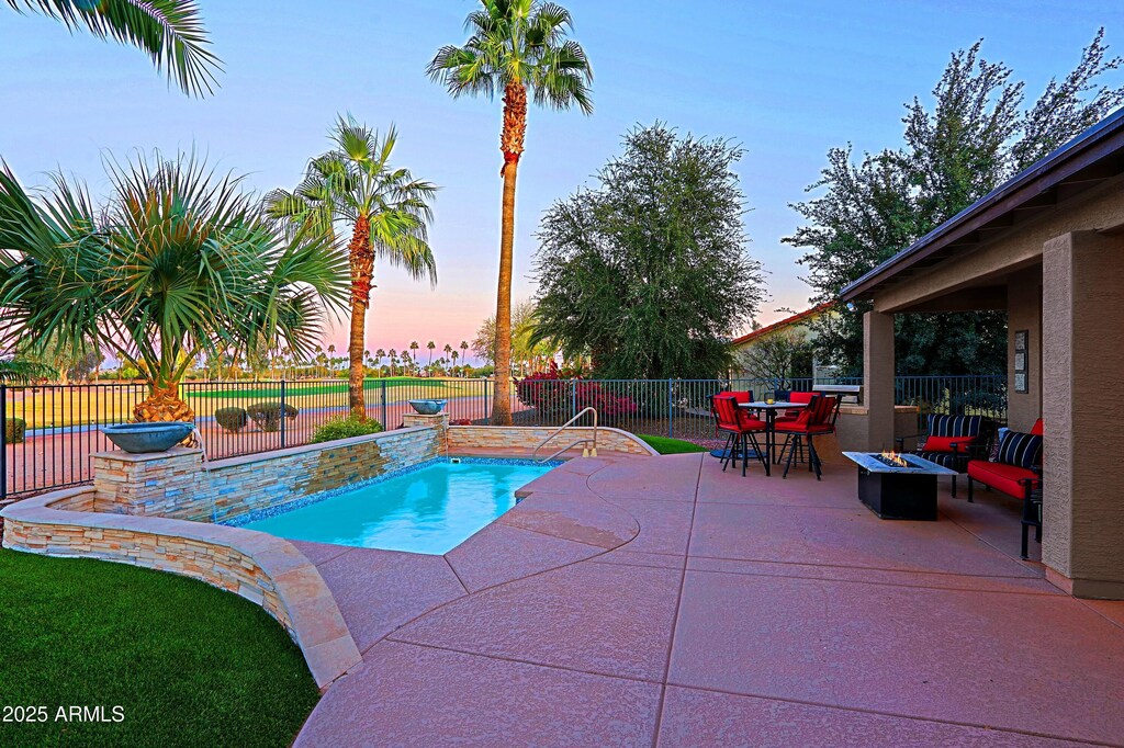 15954 W Sheila Ln, Goodyear, AZ 85395 - pool at dusk featuring a patio area, a fenced backyard, a fenced in pool, and outdoor dining area