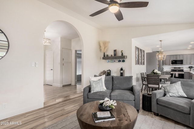 9265 E Kalil Dr, Scottsdale, AZ 85260 - living room featuring lofted ceiling, arched walkways, a ceiling fan, light wood-type flooring, and a chandelier