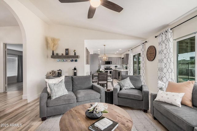 9265 E Kalil Dr, Scottsdale, AZ 85260 - living area with light wood-type flooring, arched walkways, vaulted ceiling, a ceiling fan, and baseboards