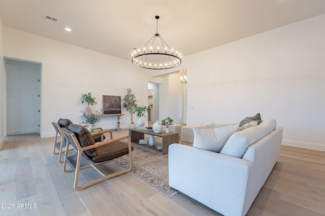 living area featuring a chandelier, visible vents, baseboards, and light wood-style floors