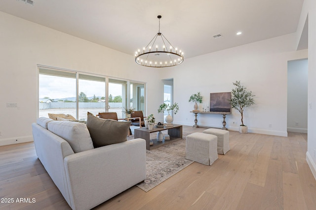 living area featuring a notable chandelier, baseboards, light wood-type flooring, and visible vents