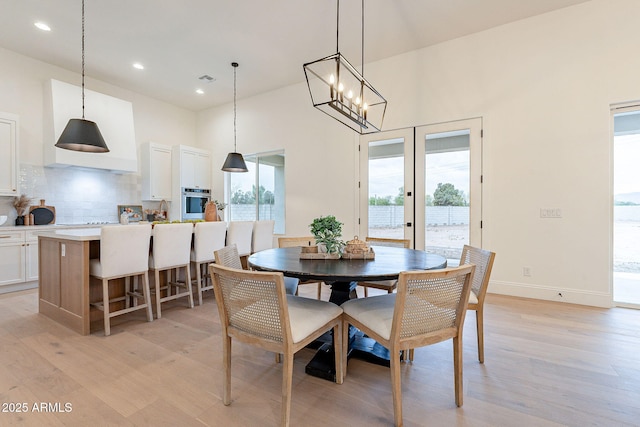 dining space featuring a high ceiling, recessed lighting, baseboards, and light wood finished floors