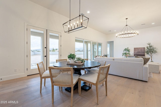 dining room with a notable chandelier, a healthy amount of sunlight, light wood-type flooring, and baseboards