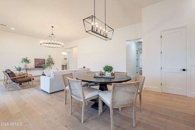 dining space with visible vents, a chandelier, and light wood finished floors