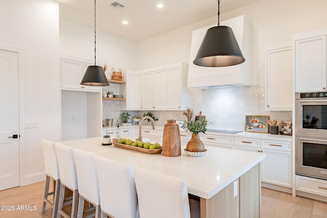 kitchen featuring visible vents, black electric stovetop, double oven, and light countertops