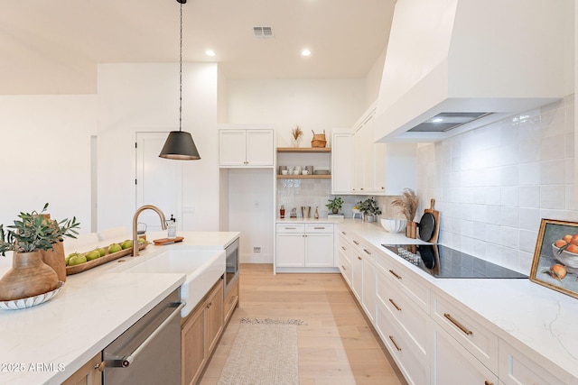 kitchen featuring visible vents, light wood-style flooring, a sink, appliances with stainless steel finishes, and wall chimney exhaust hood