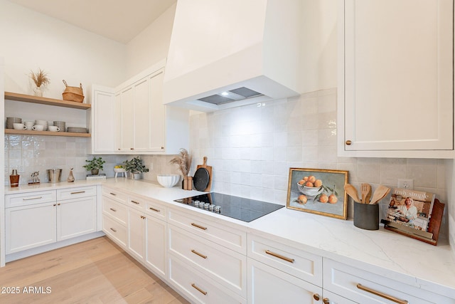 kitchen featuring custom exhaust hood, open shelves, light wood-style floors, white cabinetry, and black electric cooktop