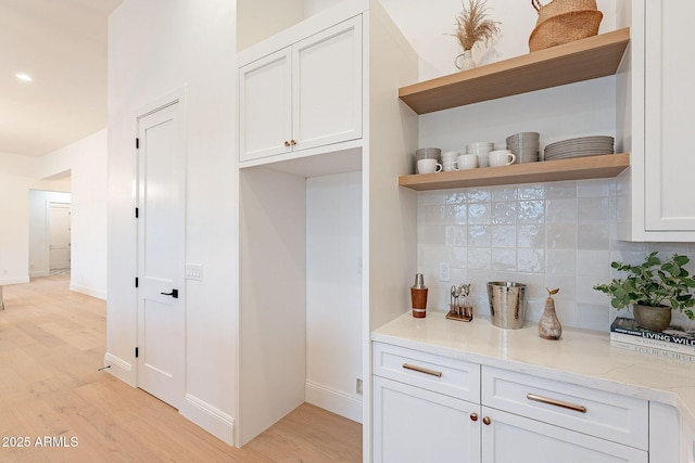 interior space with light wood-type flooring, baseboards, and decorative backsplash