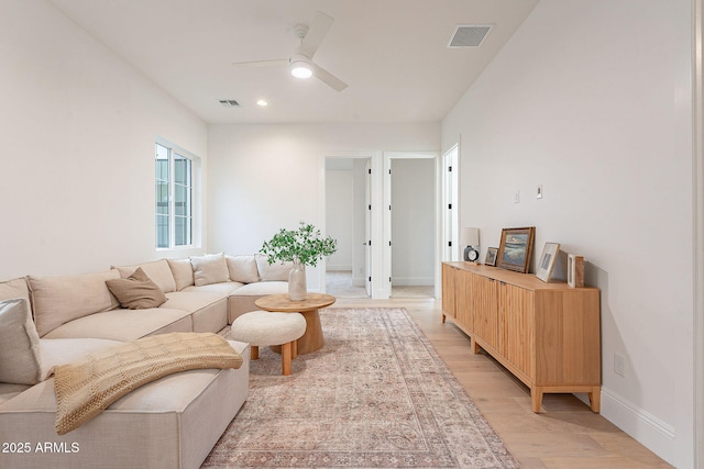 living room with light wood-type flooring, visible vents, baseboards, and ceiling fan