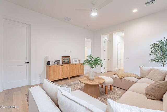 living area featuring light wood finished floors, visible vents, baseboards, and a ceiling fan