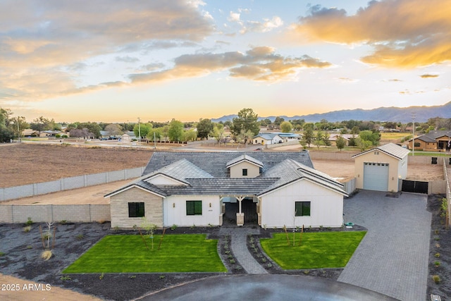 modern farmhouse style home with a mountain view, a lawn, driveway, and fence