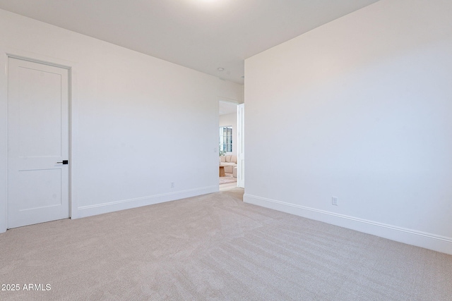 spare room with baseboards and light carpet