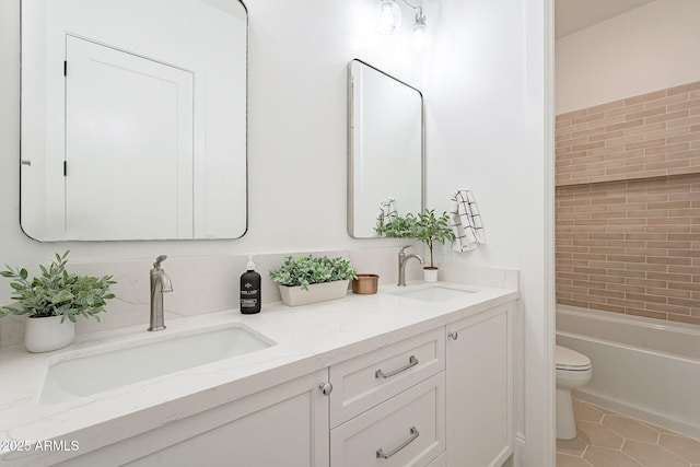 bathroom featuring tile patterned flooring, double vanity, toilet, and a sink