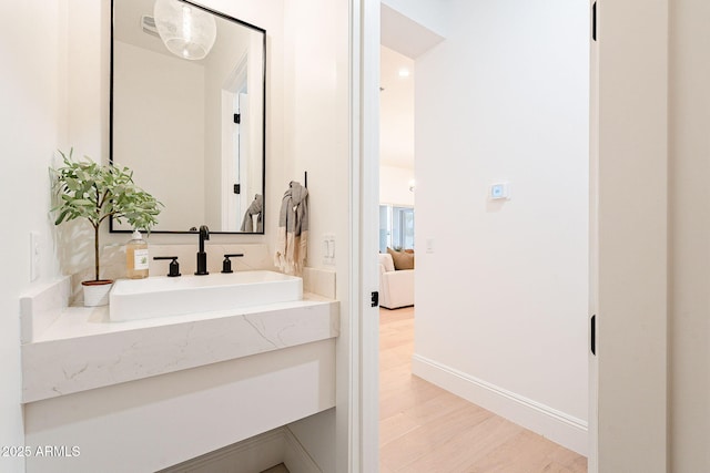 ensuite bathroom with baseboards, ensuite bath, wood finished floors, and vanity