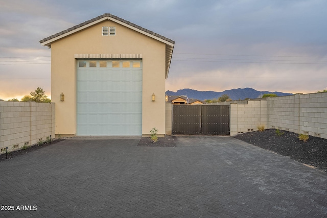 garage featuring a gate, fence, a mountain view, and driveway