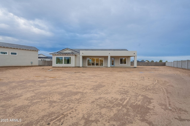 back of property with stucco siding and fence