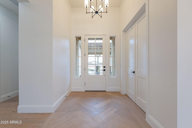 foyer entrance with visible vents, baseboards, a notable chandelier, and a towering ceiling