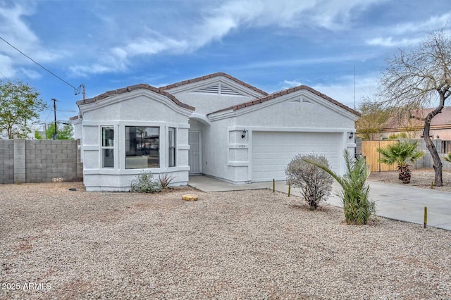 view of front facade with fence, driveway, an attached garage, stucco siding, and a tiled roof