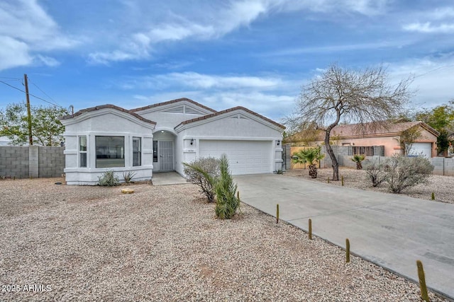 view of front of home featuring concrete driveway, fence, a garage, and stucco siding