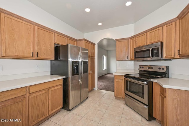 kitchen with light countertops, arched walkways, and stainless steel appliances