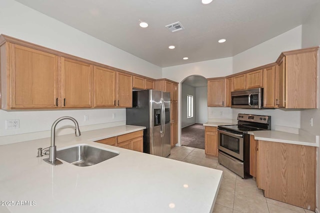 kitchen with light tile patterned floors, visible vents, arched walkways, a sink, and appliances with stainless steel finishes