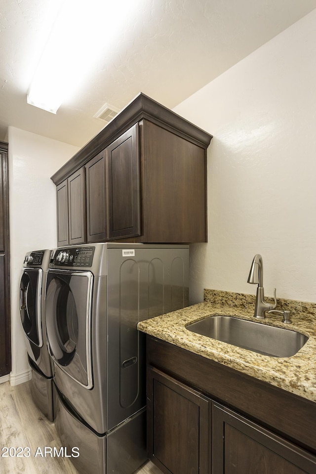 29771 N 67th St, Scottsdale, AZ 85266 - clothes washing area with separate washer and dryer, a sink, light wood finished floors, visible vents, and cabinet space