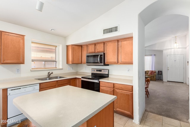 kitchen featuring light tile patterned flooring, appliances with stainless steel finishes, sink, a center island, and vaulted ceiling