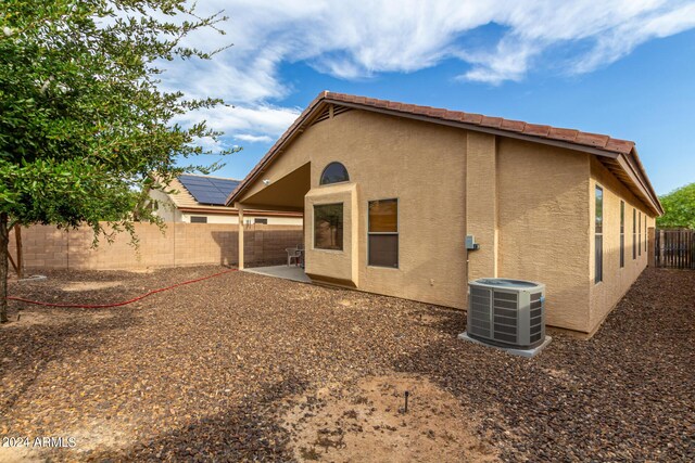 rear view of property featuring central air condition unit, solar panels, and a patio area