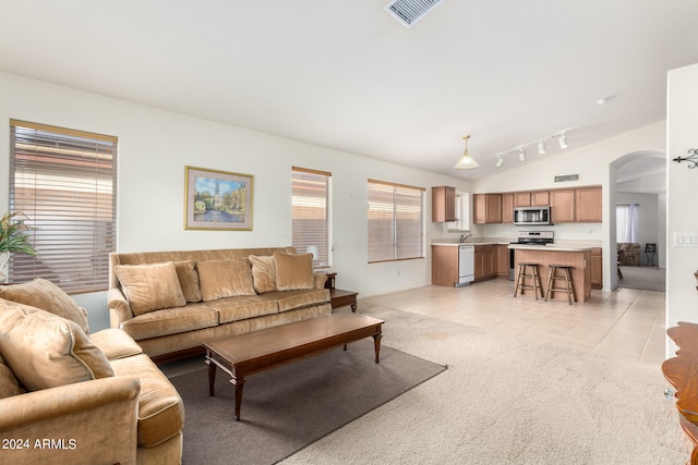 living room featuring light tile patterned floors, sink, lofted ceiling, and rail lighting