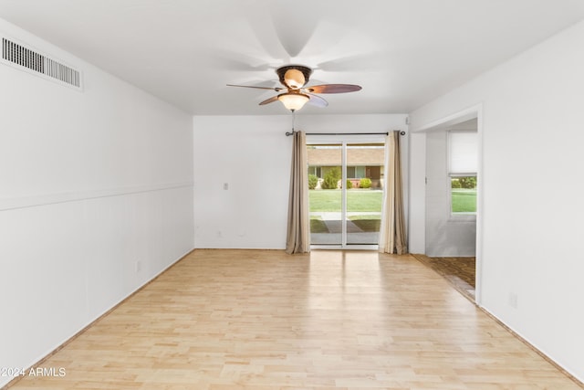 empty room with visible vents, ceiling fan, and wood finished floors