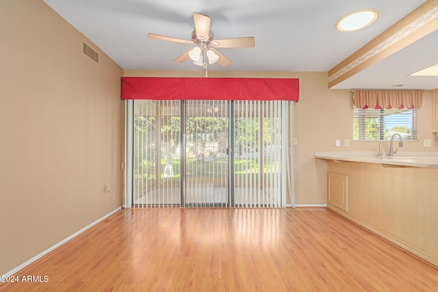 unfurnished living room with ceiling fan, light wood-type flooring, and sink