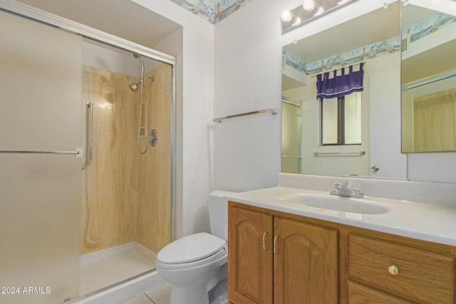 bathroom with tile patterned floors, a shower with door, vanity, and toilet