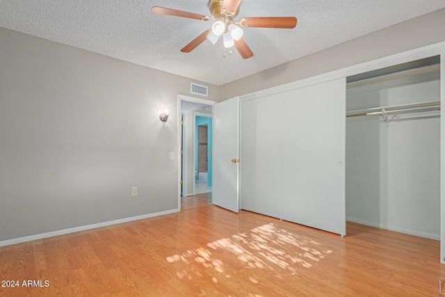 unfurnished bedroom with a textured ceiling, a closet, light hardwood / wood-style flooring, and ceiling fan